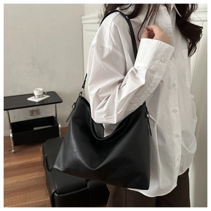 Side view of a black leather tote bag with adjustable silver buckle shoulder strap