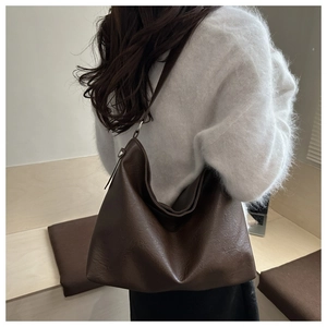 Detail of dark brown hobo shoulder bag in vintage PU leather on white sweater