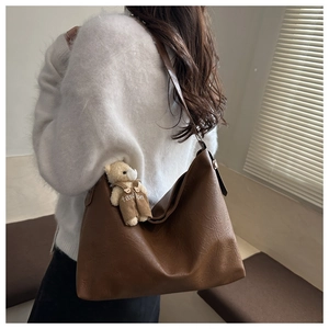Detail of dark brown faux leather hobo bag with a cute teddy bear charm on shoulder
