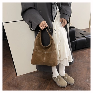 Dettaglio della borsa tote in pelle scamosciata marrone con cuciture a vista