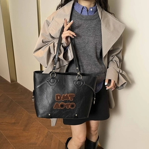 Grand sac fourre-tout noir vintage avec broderie porté par un mannequin en trench