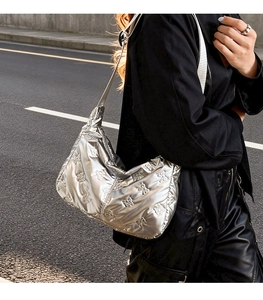 Gros plan d'un sac à bandoulière argenté matelassé avec broderie nœud et texture bouffante