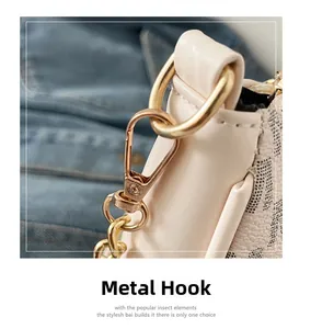Detailed close-up of golden hardware hook and chain on cream monogram crossbody bag