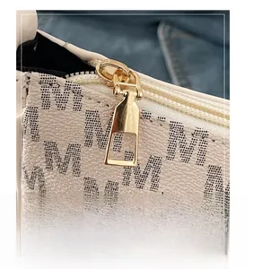 Close-up of smooth gold metal zipper on beige lychee leather bag with M pattern