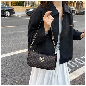 Detail of vintage crossbody bag with brown monogram pattern and golden M logo hardware