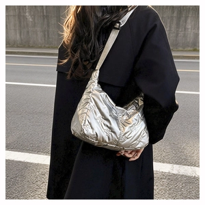 Détail du sac bandoulière argenté matelassé avec broderie nœud et fini métal brillant