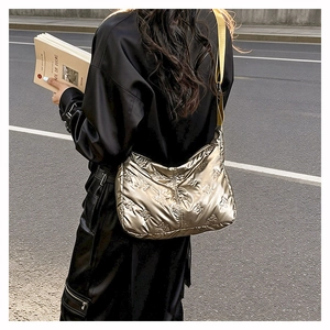 Gros plan du sac à bandoulière champagne métallisé avec motifs nœuds matelassés et sangle