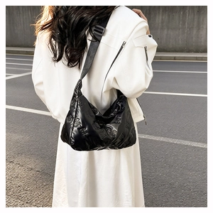 Gros plan du sac à main rembourré noir brillant avec des motifs de papillons matelassés