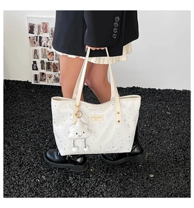 Close-up of a white tote bag with silver star prints and a plush cloud charm accessory
