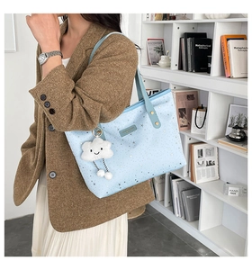 Light blue star pattern tote bag detail with white cloud plush charm and shoulder strap