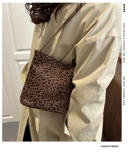 Dettaglio della borsa a secchiello leopardata con tracolla marrone su trench beige