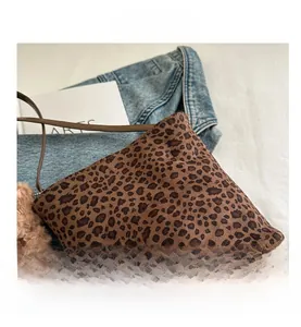 Dettaglio della borsa a secchiello leopardata con finitura opaca e ciondolo a orsetto