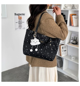 Detail of black star print canvas tote bag featuring a cute cloud plush charm
