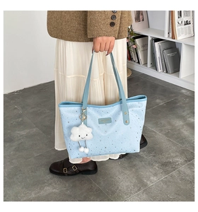 Detail of blue tote bag with star patterns and a white cloud plush charm accessory