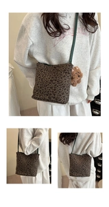 Detail view of large leopard print tote with green strap and plush bear charm