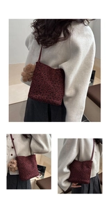 Detail of burgundy leopard print bucket bag with a cute plush bear charm on white coat