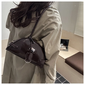 Detail of dark brown glossy patent leather underarm bag with silver metal nameplate