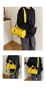 Macro shot of yellow cylinder travel bag showing zipper and adjustable shoulder strap