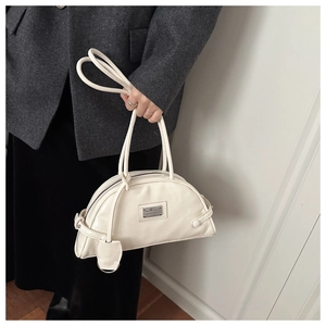Detailed view of a white semi-circular shoulder bag with a glossy finish on a female model