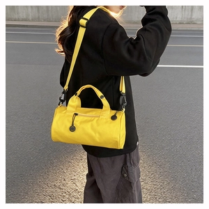 Vue détaillée du sac de sport cylindrique jaune avec bandoulière et poignée robuste