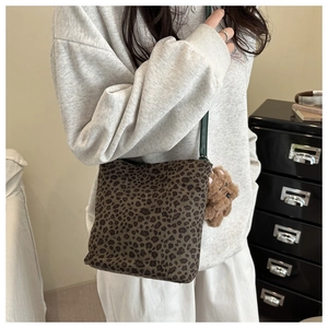 Dettaglio della borsa a secchiello leopardata con ciondolo a orsetto e tracolla verde scuro
