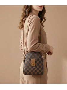 Close-up of vintage checkered crossbody phone bag with brown leather flap and metal buckle