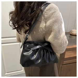 Détail du sac cabas plissé noir avec nœud et étoile sur un pull en maille douce