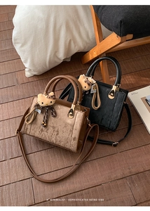 Detail of retro corduroy handbag with leather trim and gold hardware in warm indoor setting