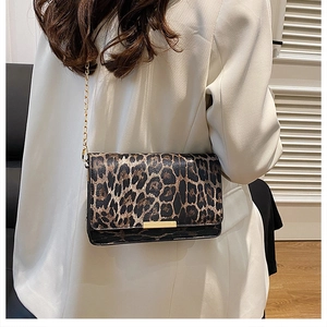 Detail of leopard print crossbody bag with gold chain strap on white blazer