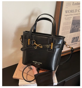 Detail of black leather bucket bag featuring gold hardware and Maven & Chic logo printing