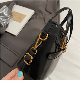 Detail of high-quality gold metal hook and buckle on a black leather bucket handbag