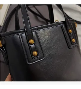 Detailed close-up of vintage golden hardware on black lychee grain leather bucket bag