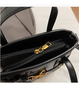 Detail view of smooth golden zipper and interior compartment of black leather bucket bag