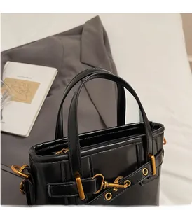 Detailed close-up of a black leather handbag with gold metal buckles and rivets