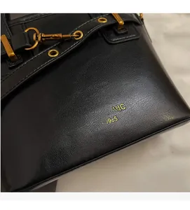 Close-up of black lychee-textured leather bucket bag with golden Maven & Chic logo