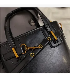 Close-up of black lychee grain leather bucket bag featuring vintage gold metal hardware
