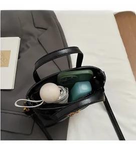 Interior view showing the large capacity of a black leather bucket bag with daily items