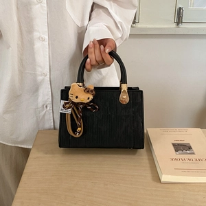 Elegant black vertical striped handbag with plush leopard bow charm and gold hardware