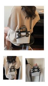 Detail of retro small bucket bag in cream woven fabric with black leather straps and gold buckle