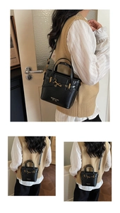 Detail view of black leather bucket bag featuring gold hardware and logo branding