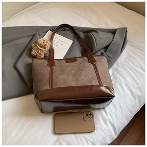 Detailed shot of brown textured tote bag with teddy bear charm and sleek leather accents
