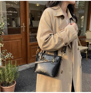Detail of black leather bucket bag with gold buckles and logo on stylish street background