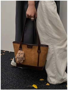 Detail of vintage tote bag with embossed pattern, faux leather finish and bear charm