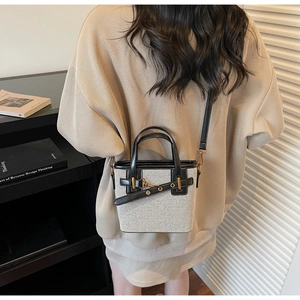 Model wearing a stylish mini bucket bag in beige fabric with black leather handles