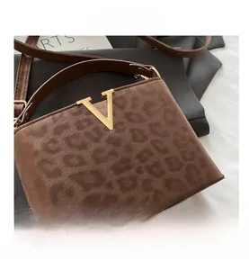 Close-up of leopard print faux suede handbag featuring a gold V-shaped metal hardware buckle
