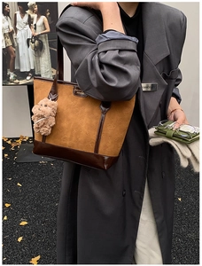 Chic brown suede tote bag with cat embossing and plush bear charm on a street model