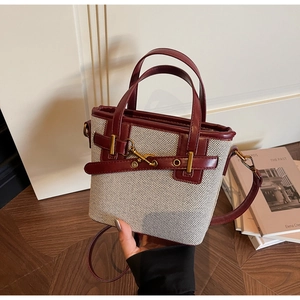 Detail view of houndstooth plaid bucket bag with burgundy leather trim and gold hardware