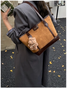 Sac cabas en simili daim marron avec motifs gaufrés et breloque ours porté par un mannequin