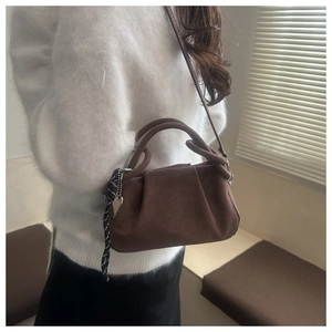Dettaglio di una borsa tote vintage in pelle scamosciata marrone con design arricciato