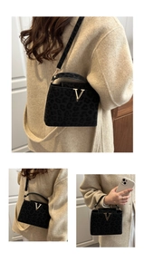 Detail of black leopard print crossbody bag with golden V-shaped lock and suede texture